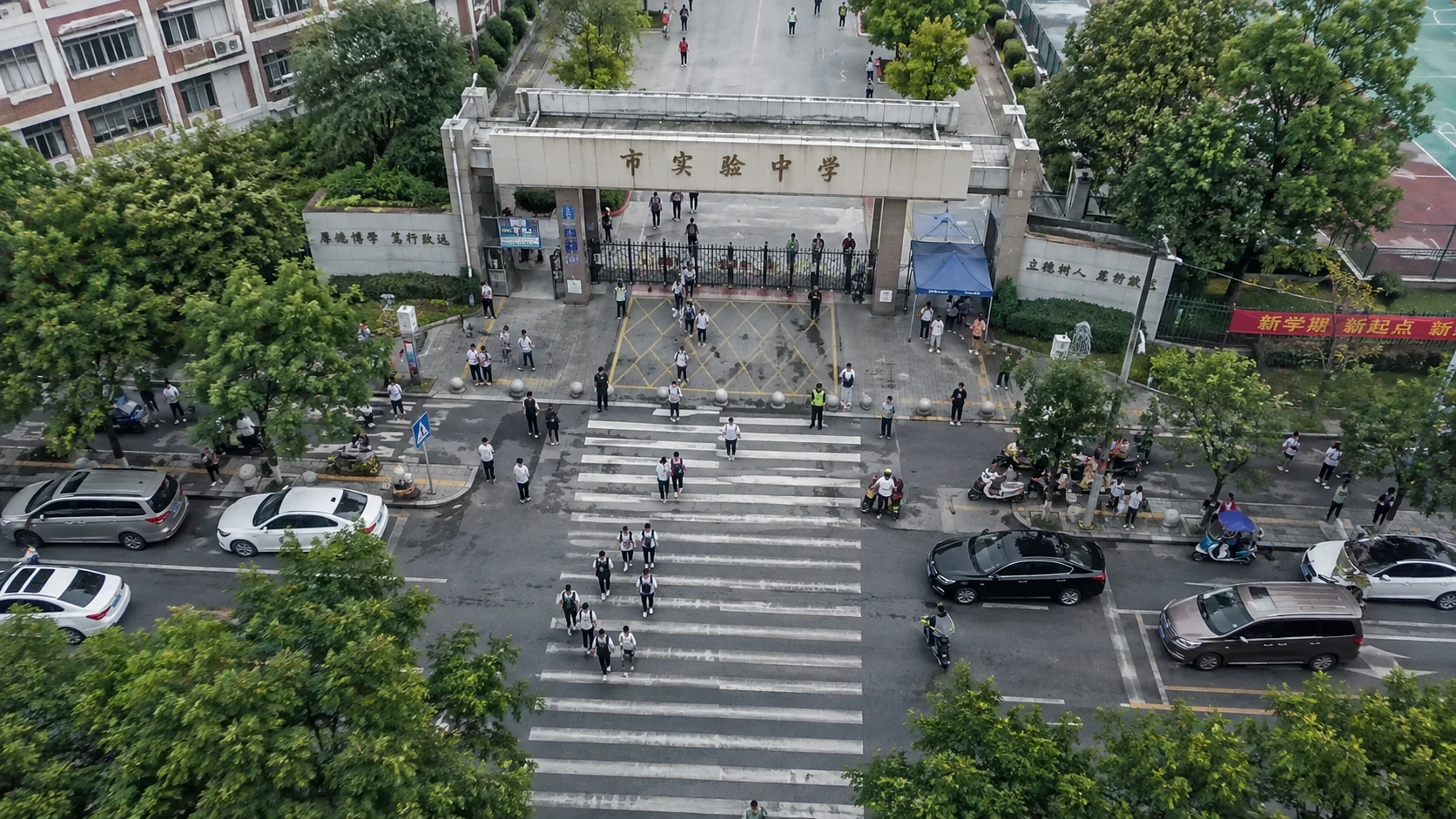校门人车交汇风险巡查:独立无人机航拍场景与红色目标标注示意
