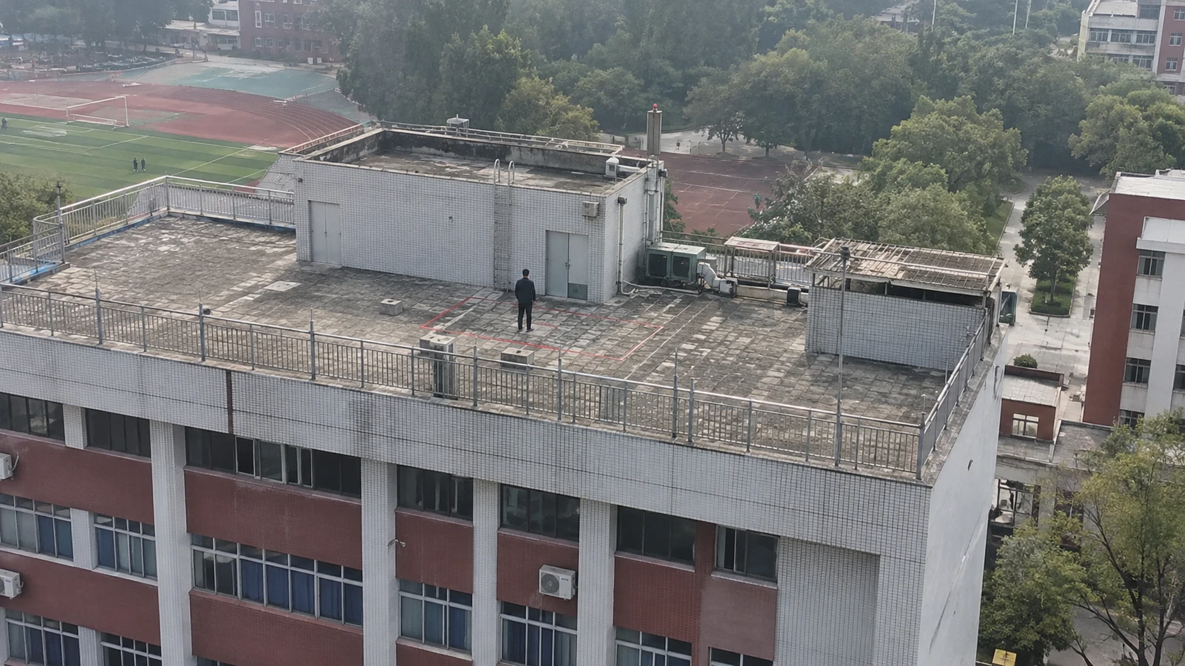 校园屋顶危险区域进入巡查:独立无人机航拍场景与红色目标标注示意